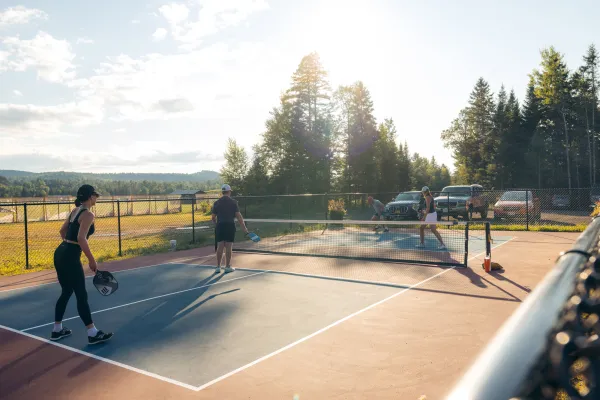 Four people play a match of pickleball on a pickleball court outside. 